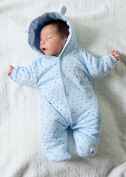 Newborn baby wearing a blue onesie with a hood on a white blanket